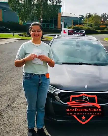 Learner holding a practical driving test pass certificate beside the Alma Driving School grey DS 4